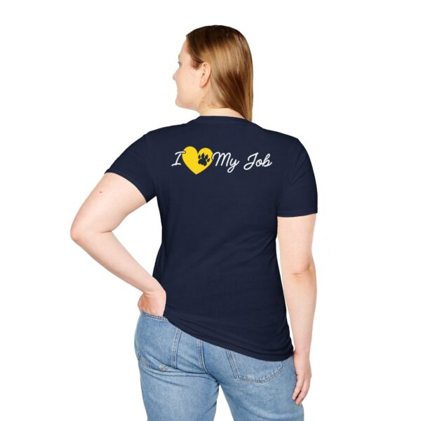 A woman viewed from the back, wearing a navy blue T-shirt with the text "I [heart] My Job", where the heart is represented by a yellow puzzle piece, paired with light blue jeans.